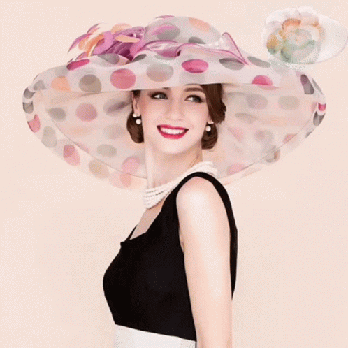 A Woman Wearing A Black And White Dress And A Polka Dot Hat GIF