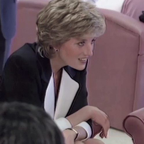 A Woman Wearing A Black And White Jacket Is Sitting In A Chair Talking To Someone . GIF