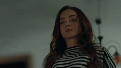 A Woman Wearing A Black And White Striped Shirt Is Looking At The Camera GIF