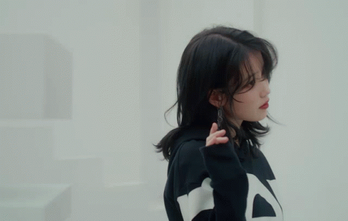 A Woman Wearing A Black And White Striped Sweatshirt Holds Her Hand To Her Face GIF
