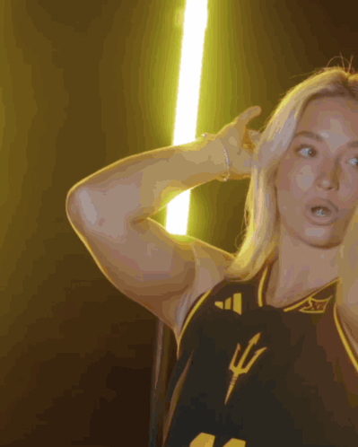 a woman wearing a black and yellow jersey with a trident on the front