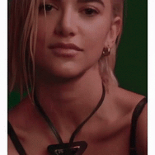 A Woman Wearing A Black Bra And A Necklace With A Triangle Pendant GIF