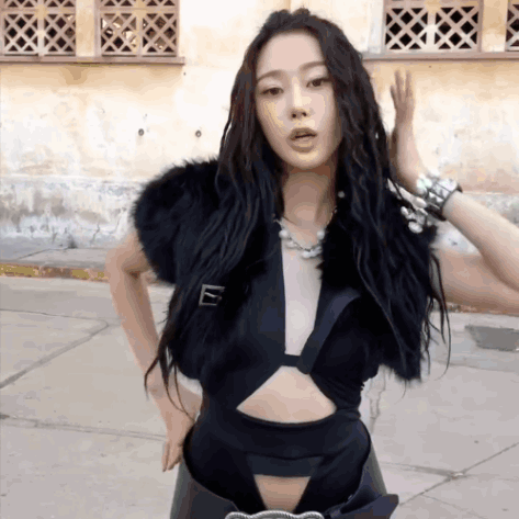 A Woman Wearing A Black Crop Top And A Fur Vest GIF