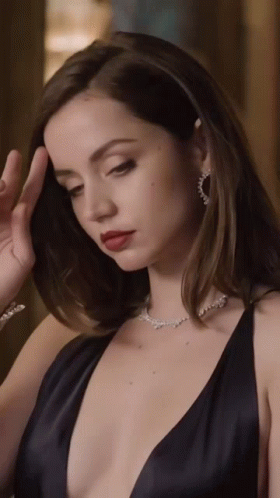 A Woman Wearing A Black Dress And A Necklace With Diamonds GIF