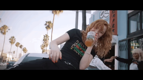 a woman wearing a black gucci t-shirt drinks from a glass