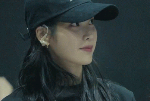 a woman wearing a black hat and earrings is crossing her arms