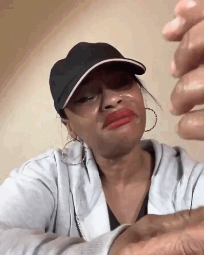 a woman wearing a black hat and earrings is crying