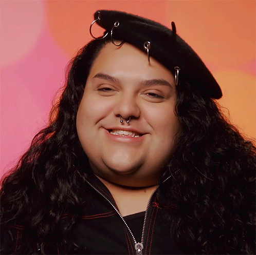 A Woman Wearing A Black Hat With Rings On It Smiles For The Camera GIF