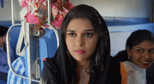A Woman Wearing A Black Head Scarf Is Sitting On A Train GIF