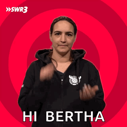 A Woman Wearing A Black Hoodie Says Hi Bertha On A Red Background GIF