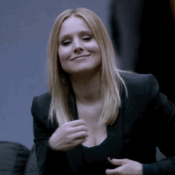 A Woman Wearing A Black Jacket And A Black Top Is Smiling GIF