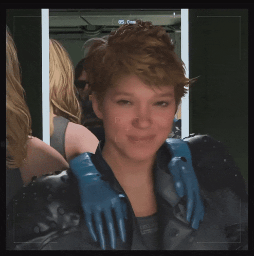 A Woman Wearing A Black Jacket And Blue Gloves Looks At The Camera With The Number 85 On The Screen GIF