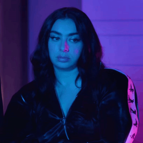 A Woman Wearing A Black Jacket With A Pink Stripe On The Sleeves Looks At The Camera GIF