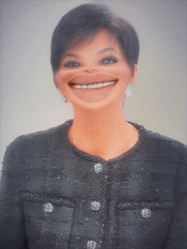 A Woman Wearing A Black Jacket With Buttons On The Front Is Smiling GIF