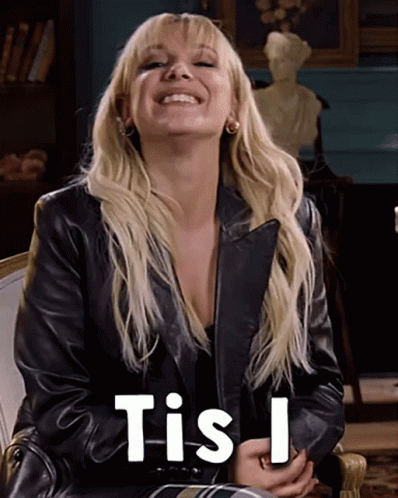 A Woman Wearing A Black Leather Jacket Is Smiling And Says Tis I . GIF