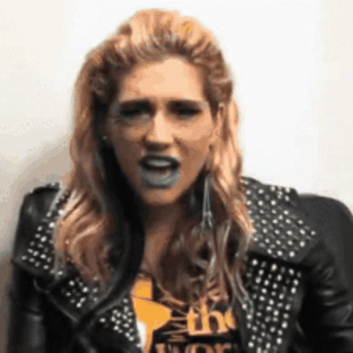 A Woman Wearing A Black Leather Jacket With Studs Is Making A Funny Face GIF