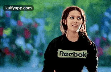 A Woman Wearing A Black Reebok Sweatshirt Is Looking Up . GIF