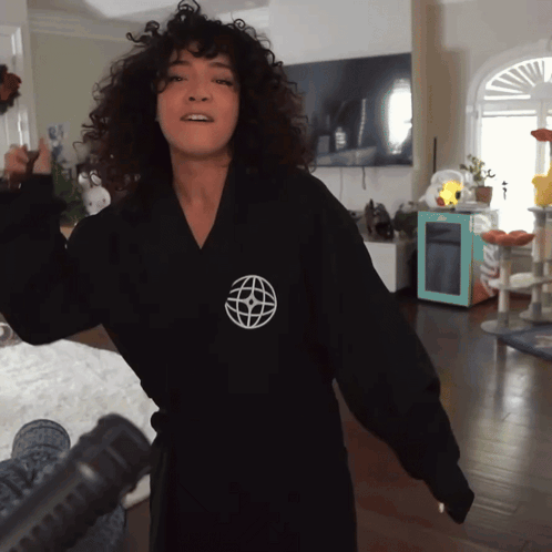 A Woman Wearing A Black Robe With A White Globe On The Front GIF