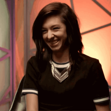 A Woman Wearing A Black Shirt And A Necklace Smiles For The Camera GIF