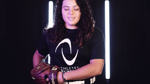 a woman wearing a black shirt that says athletes on it is holding a wilson baseball glove