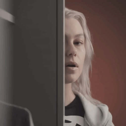 A Woman Wearing A Black Shirt With The Letter B On It Looks At Herself In The Mirror GIF