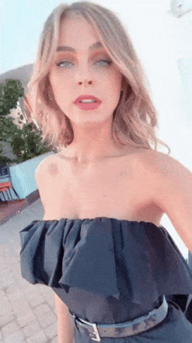 A Woman Wearing A Black Strapless Top Is Taking A Selfie With Her Eyes Closed GIF