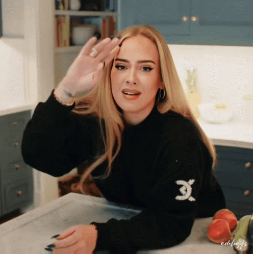 A Woman Wearing A Black Sweater With An X On The Sleeve GIF