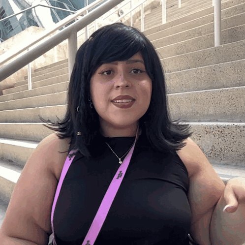 A Woman Wearing A Black Top And A Purple Lanyard That Says ' I ' On It GIF