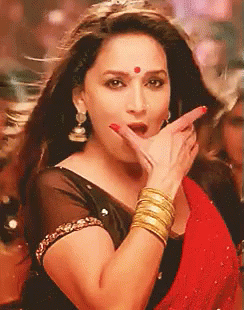 A Woman Wearing A Black Top And A Red Saree Is Making A Funny Face With Her Hand . GIF