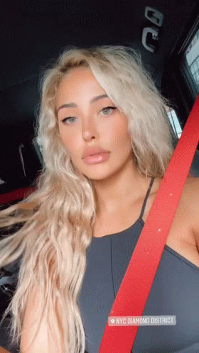 A Woman Wearing A Black Top And A Red Seat Belt Is Sitting In A Car In Nyc Diamond District GIF