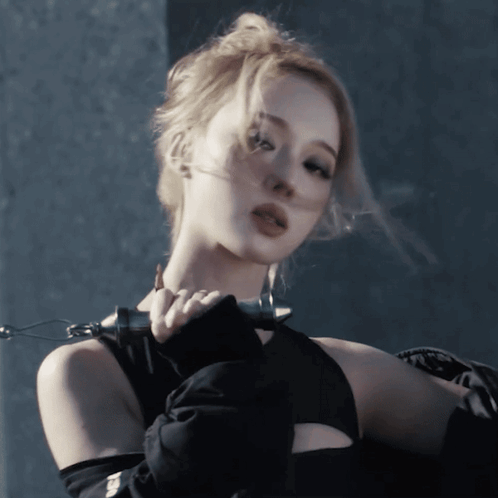 A Woman Wearing A Black Top And Gloves Holds A Chain Around Her Neck GIF