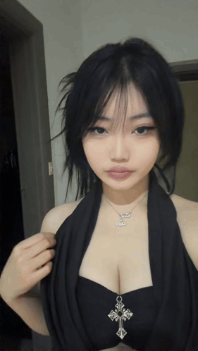 A Woman Wearing A Black Top With A Cross Necklace GIF