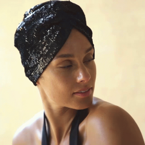 A Woman Wearing A Black Turban Looks Down At Something GIF