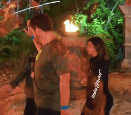 A Woman Wearing A Black Under Armour Sweatshirt Stands Next To A Man In A Green Shirt GIF