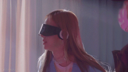 a woman wearing a blindfold and headphones is standing in a dark room .