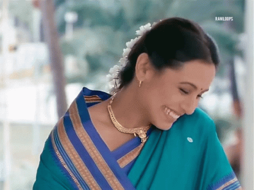 A Woman Wearing A Blue And Gold Striped Saree Is Smiling GIF