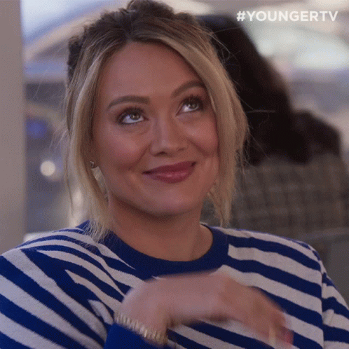 A Woman Wearing A Blue And White Striped Sweater Is Smiling And Looking Up GIF