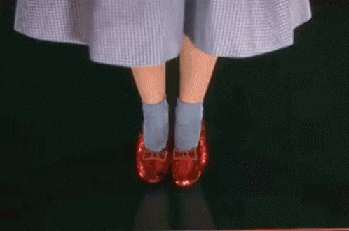 A Woman Wearing A Blue Dress And Red Shoes Is Standing On A Green Surface . GIF
