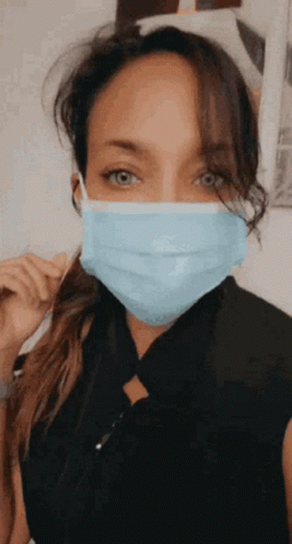 A Woman Wearing A Blue Face Mask With A Ponytail . GIF