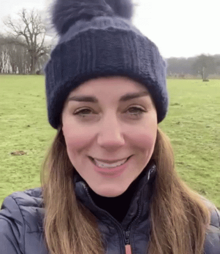 A Woman Wearing A Blue Hat And A Blue Jacket Is Smiling . GIF