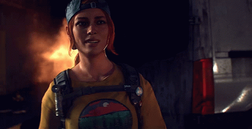 A Woman Wearing A Blue Hat And A Yellow Shirt With A Mountain On It Is Smiling GIF