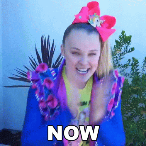 A Woman Wearing A Blue Jacket And A Pink Bow On Her Head Says " Now " GIF