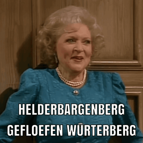 A Woman Wearing A Blue Jacket And Pearls Says Helderbergenberg Gefloeffen Wurtenberg GIF