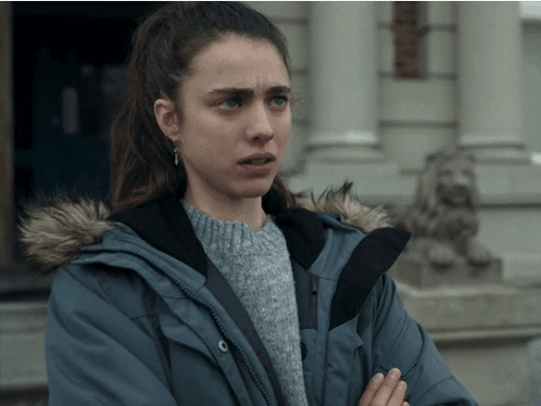 A Woman Wearing A Blue Jacket With A Fur Hood Is Standing In Front Of A Building GIF