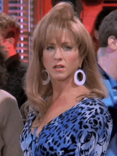 A Woman Wearing A Blue Leopard Print Dress And White Earrings Is Standing In A Crowd . GIF