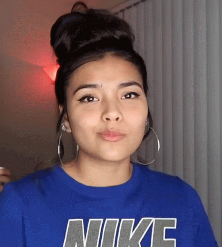 A Woman Wearing A Blue Nike Shirt With Hoop Earrings GIF
