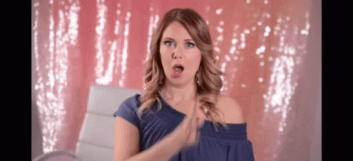 A Woman Wearing A Blue Off The Shoulder Top Is Clapping Her Hands GIF