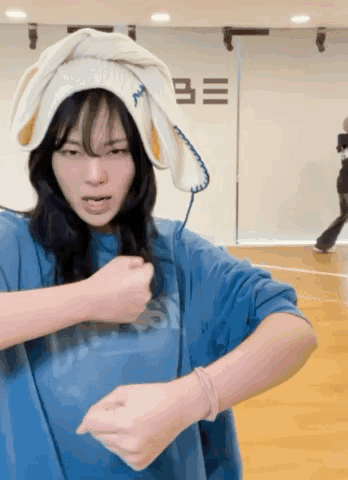 A Woman Wearing A Blue Shirt And A White Towel On Her Head Is Dancing . GIF
