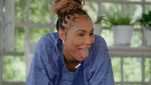 A Woman Wearing A Blue Shirt Is Sticking Out Her Tongue GIF