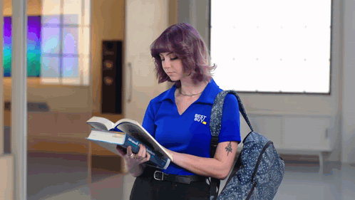A Woman Wearing A Blue Shirt That Says Best Buy Is Reading A Book GIF